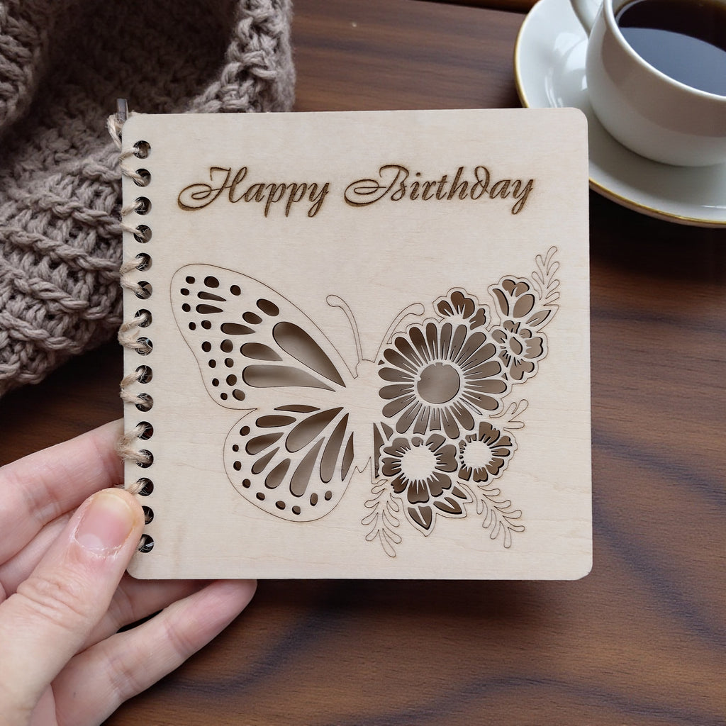 Personalised wooden birthday card held in hand, butterfly and wildflower cut-out design, 13x13 cm, engraved “Happy Birthday”