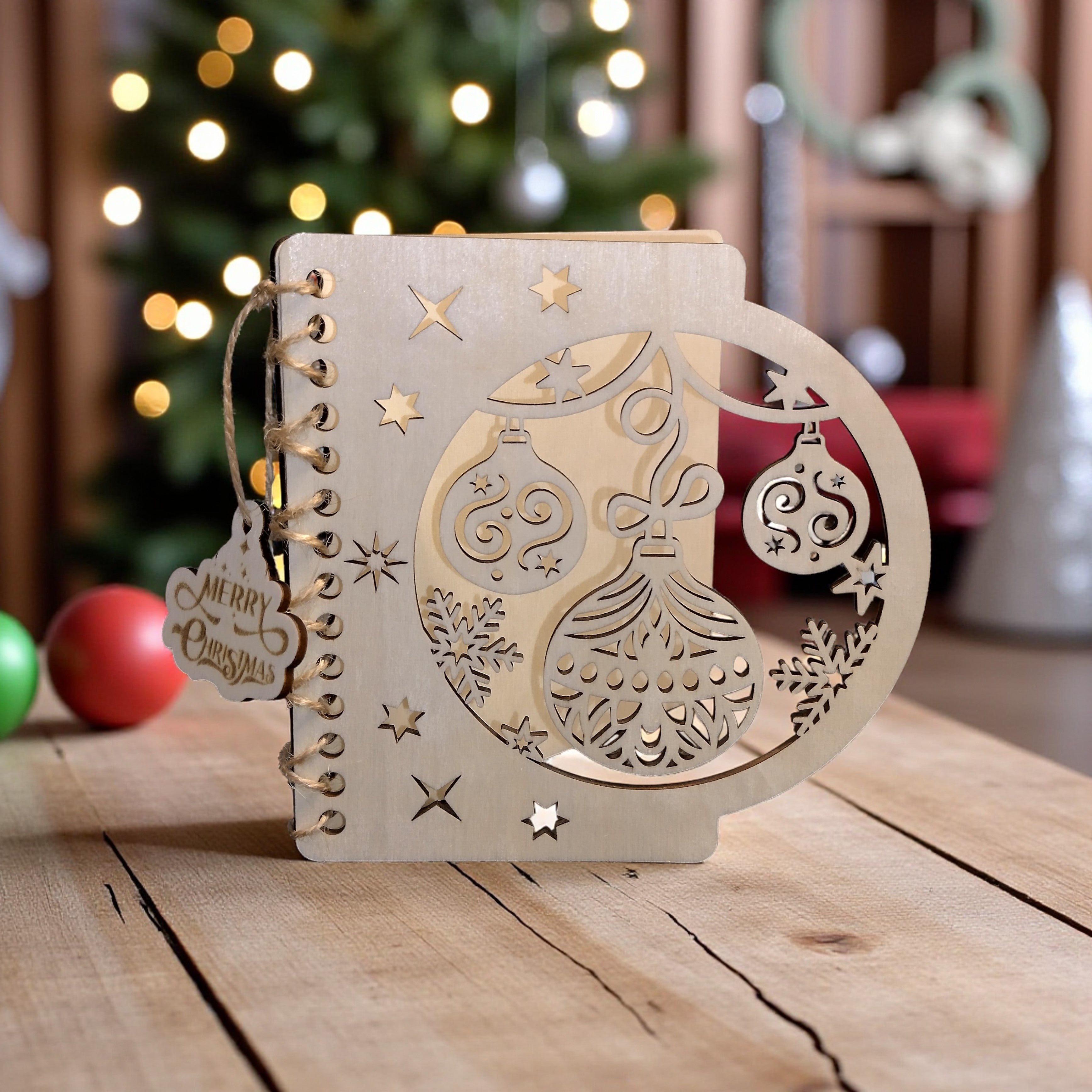 Laser-cut Merry Christmas wooden card standing on table with Christmas tree lights